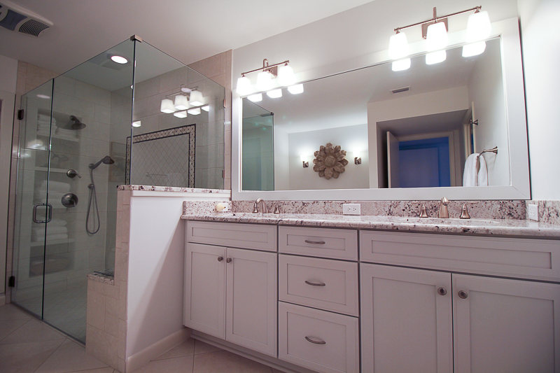Spacious vanity with 2 sinks and a drawer stack in the center for optimum storage. Note the walk-in shower with no curb with a bench seat and frameless glass enclosure.
