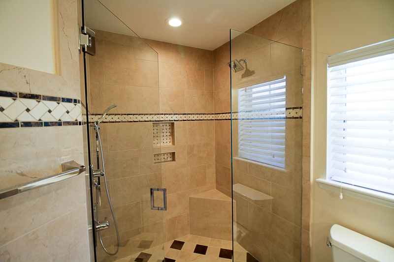 This is a custom walk in shower with no curb and corner seat. Porcelain tile in a 12 x 24 is used here and gives you the Crema Marfil Marble look at a fraction of the cost.