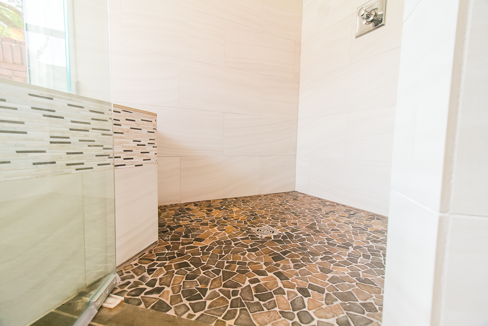 This custom walk in shower with no curb boasts a sliced natural stone used on the floor and shows its natural beauty.