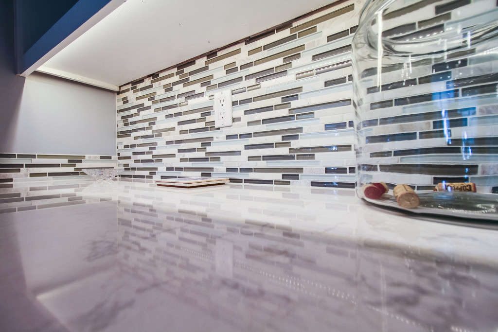 Solid surface top to look like marble shows well with the combination glass and marble backsplash.